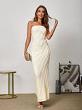 Woman holding a clutch and wearing a beige lace strapless maxi dress