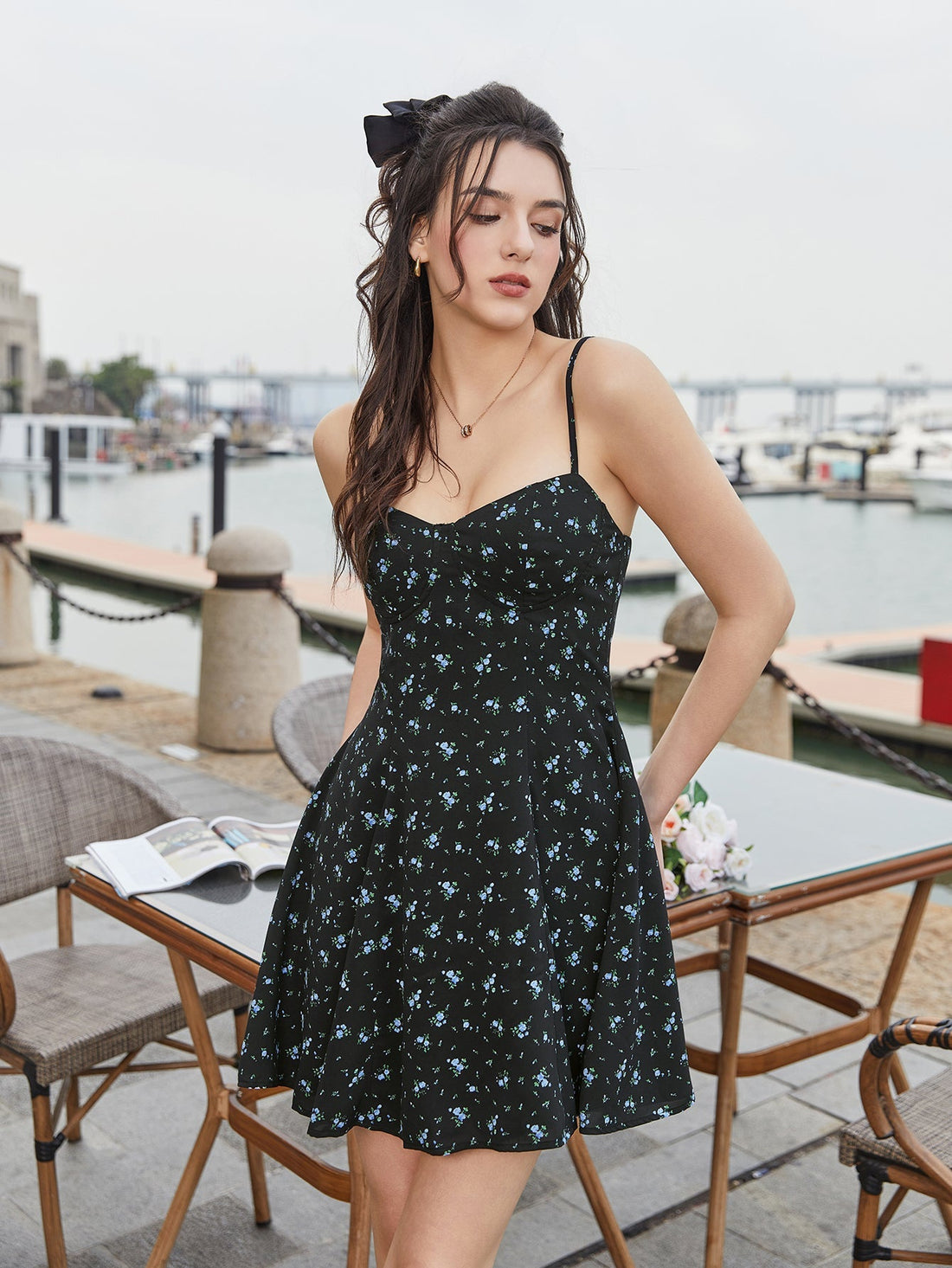 Woman wearing a black floral print mini dress with spaghetti straps