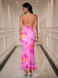 Back view of a woman in a pink floral print mesh trumpet dress with a low back and tie closure.