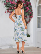 Back view of a woman in a white midi dress with a blue floral print, showcasing the tiered skirt and strapless design.