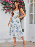Woman wearing a white midi dress with a blue floral print, sweetheart neckline, and tiered skirt.