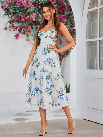 Woman wearing a white midi dress with a blue floral print, sweetheart neckline, and tiered skirt.
