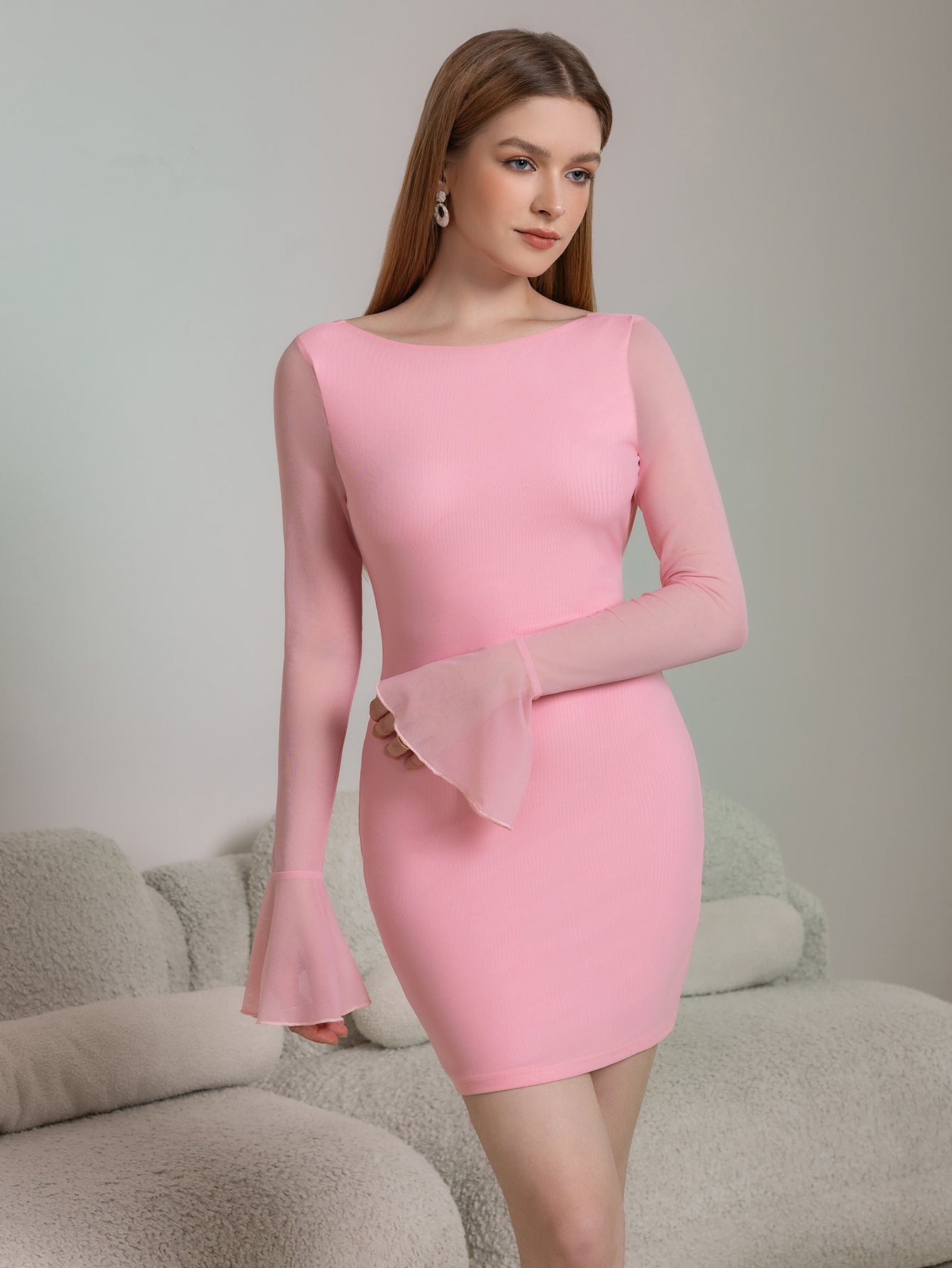 Front view of a woman wearing a pink bodycon dress with sheer sleeves.