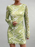 Close-up of a woman's torso in a green abstract print mesh mini dress
