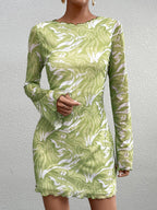 Close-up of a woman's torso in a green abstract print mesh mini dress