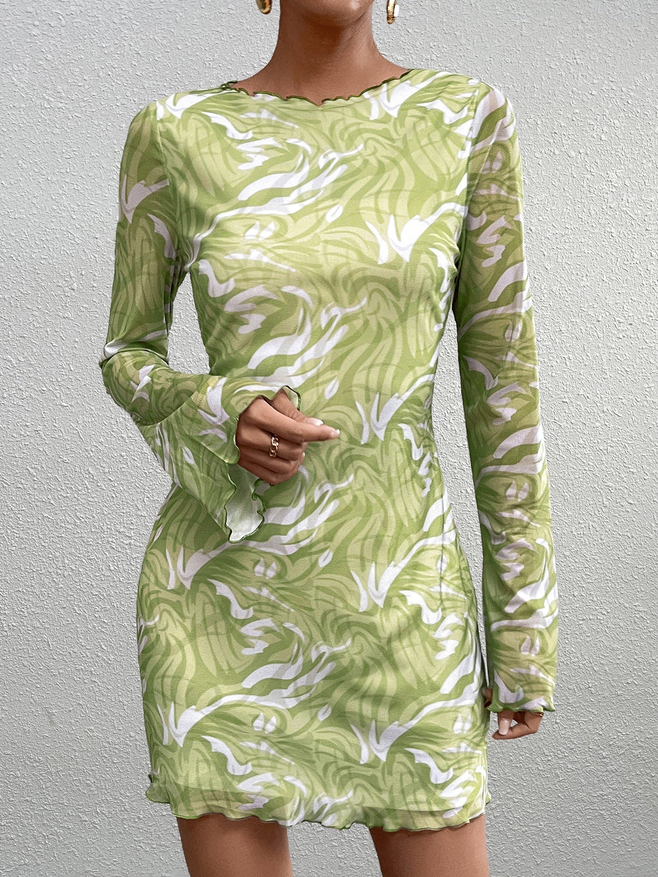 Close-up of a woman's torso in a green abstract print mesh mini dress