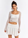 Full body shot of a woman in a white sheer mesh crop top and white mini skirt.