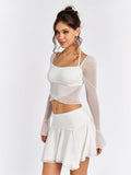 Side view of a woman in a white sheer mesh crop top and white mini skirt.