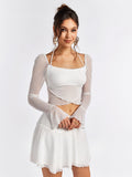 Front view of a woman modeling a white sheer mesh crop top with flared sleeves.
