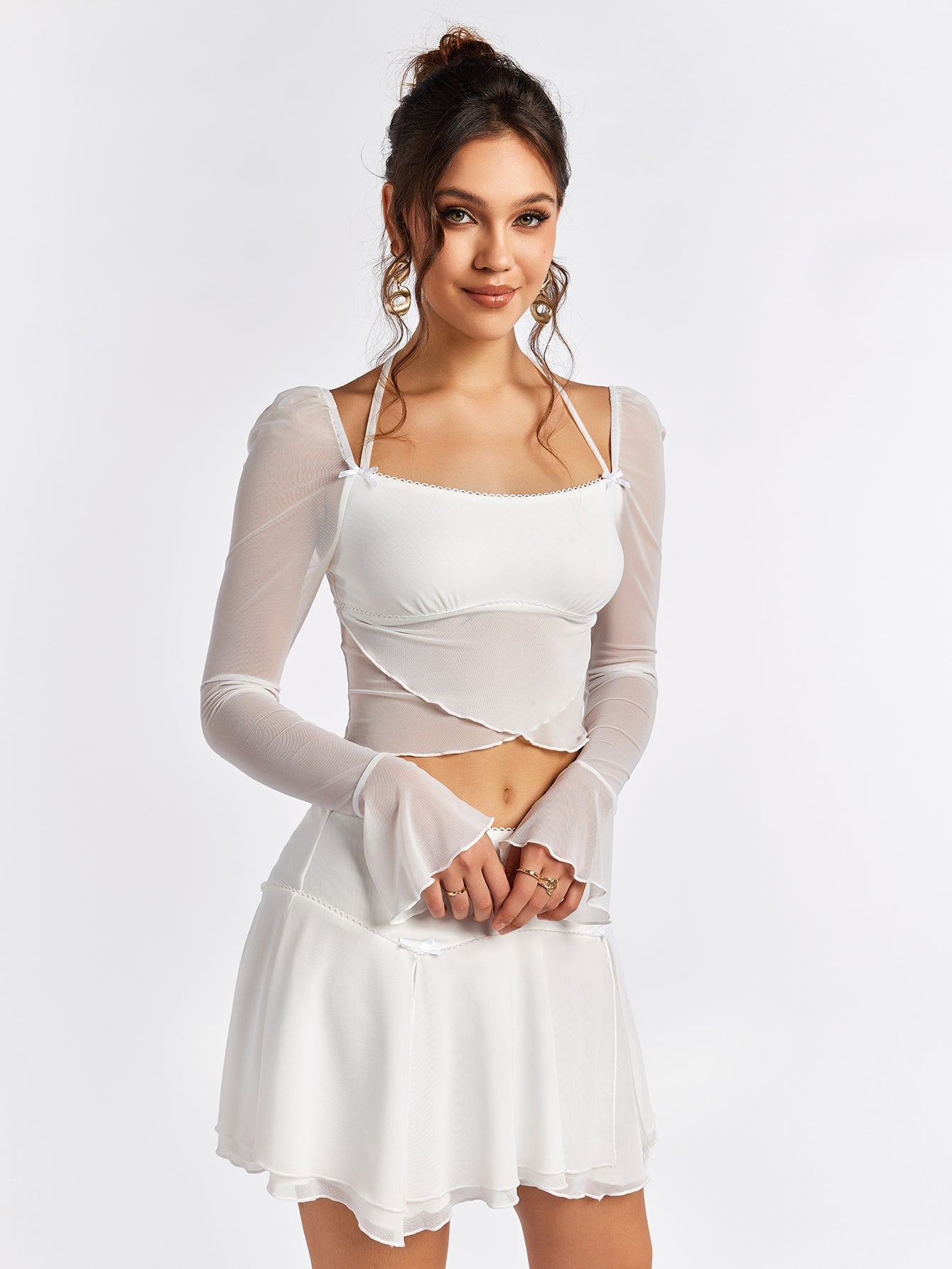 Front view of a woman modeling a white sheer mesh crop top with flared sleeves.