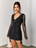 Full-body shot of a woman in a black sheer mesh mini dress with a tie-front neckline