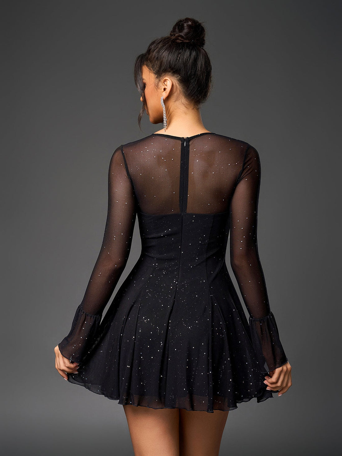 Woman in a black sparkly mesh dress with long bell sleeves and a keyhole neckline