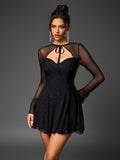 Front view of a woman wearing a black sparkly mesh dress with a tie-front keyhole neckline