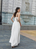 Woman in a white maxi dress with ruffled trim and spaghetti straps from the back.