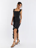 Model wearing black satin sheath dress with floral applique and asymmetrical hem