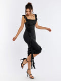 Model posing in black satin sheath dress with ruffled detailing