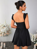 Back view of a woman in a black fit and flare mini dress with ruched cap sleeves