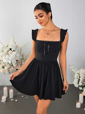 Woman wearing a black fit and flare mini dress with ruched cap sleeves and a square neckline