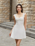Woman wearing a white satin fit and flare dress with ruffled straps and a ruched sweetheart neckline, posing outdoors.
