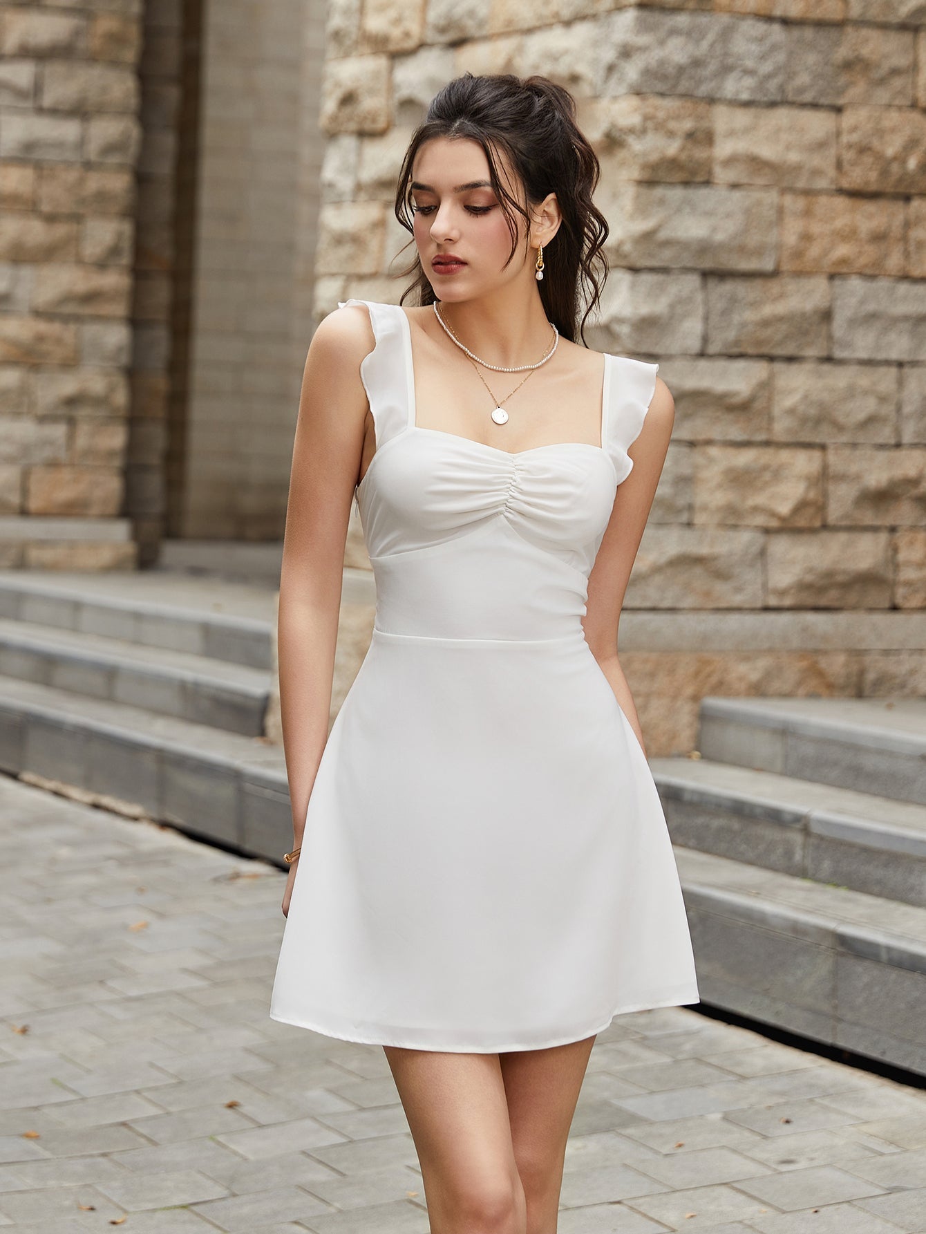 Model in a white ruched bodice dress with flared skirt, looking down.