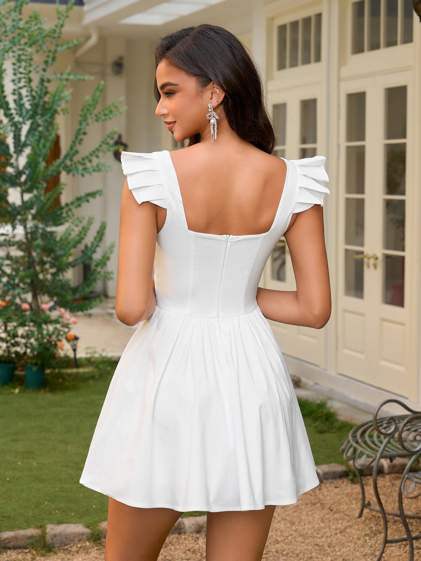 Back view of a woman in a white fit and flare dress with a square neckline