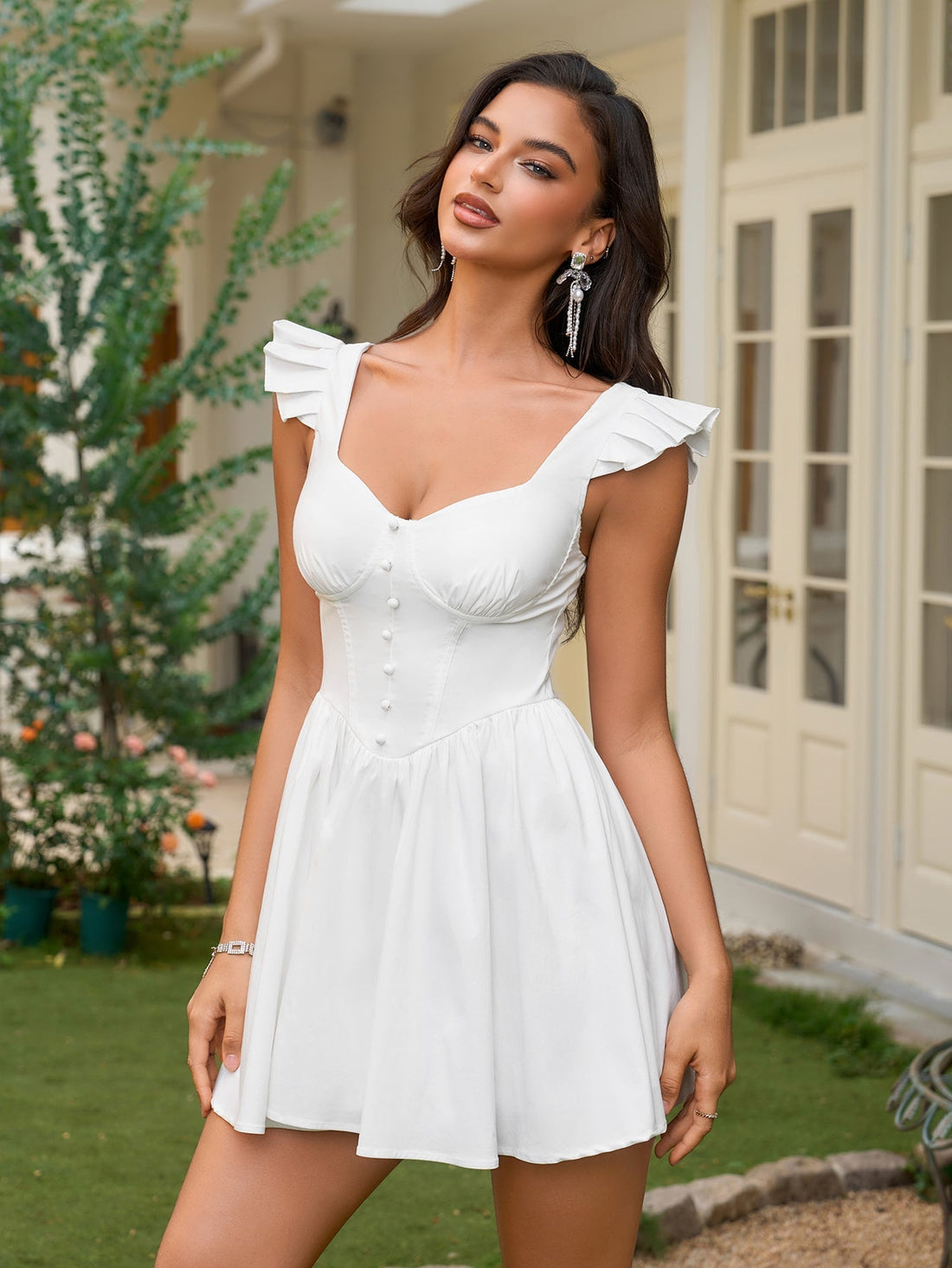 Woman wearing a white short dress with ruffled cap sleeves and a button-front bodice