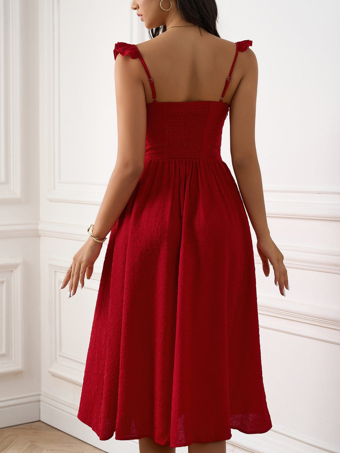 Woman wearing a red textured A-line midi dress with ruffled cap sleeves and a sweetheart neckline, standing with her right leg forward to show a high slit.