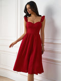 Woman in a red textured A-line midi dress with ruffled cap sleeves and a sweetheart neckline, posing with her hand on her hip.