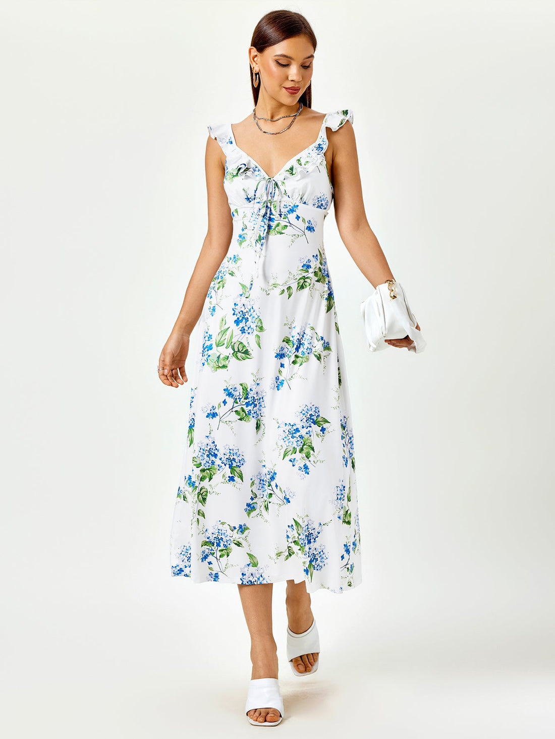 Woman wearing a white midi dress with a blue floral print, featuring ruffled straps and a tie-front detail.