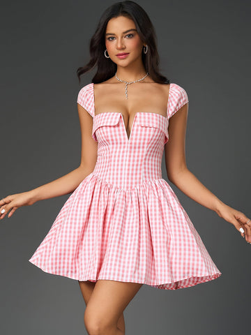 Woman wearing a pink and white gingham check fit and flare dress with a plunging neckline and cap sleeves.