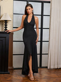 Full length shot of a woman in a black halter neck formal dress with a dramatic flowing skirt.
