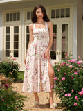 Woman standing in a garden wearing a floral print halter neck midi dress with a high slit.