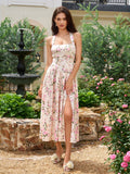 Woman wearing a floral print halter neck midi dress with a high slit, standing outdoors.
