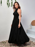 Front three-quarter view of a woman in a black halter neck maxi dress.