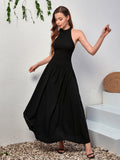 Woman modeling a black halter neck maxi dress, showing the flow of the skirt.