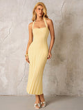 Full body shot of a woman in a yellow ribbed knit halter midi dress.