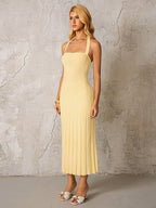 Side view of a woman in a yellow ribbed knit halter midi dress.