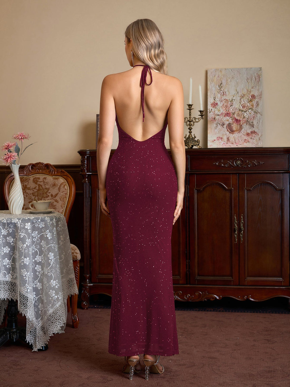 Woman wearing a burgundy sparkling halter neck floor-length trumpet dress, front view.