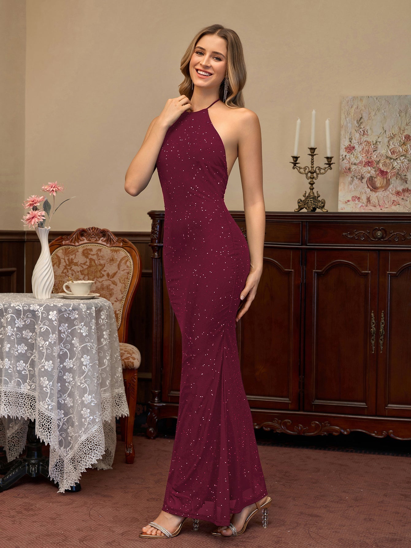 Woman wearing a burgundy sparkling halter neck floor-length trumpet dress, side view.