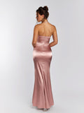 Back view of a woman in a pink satin floor-length mermaid gown with a halter neckline