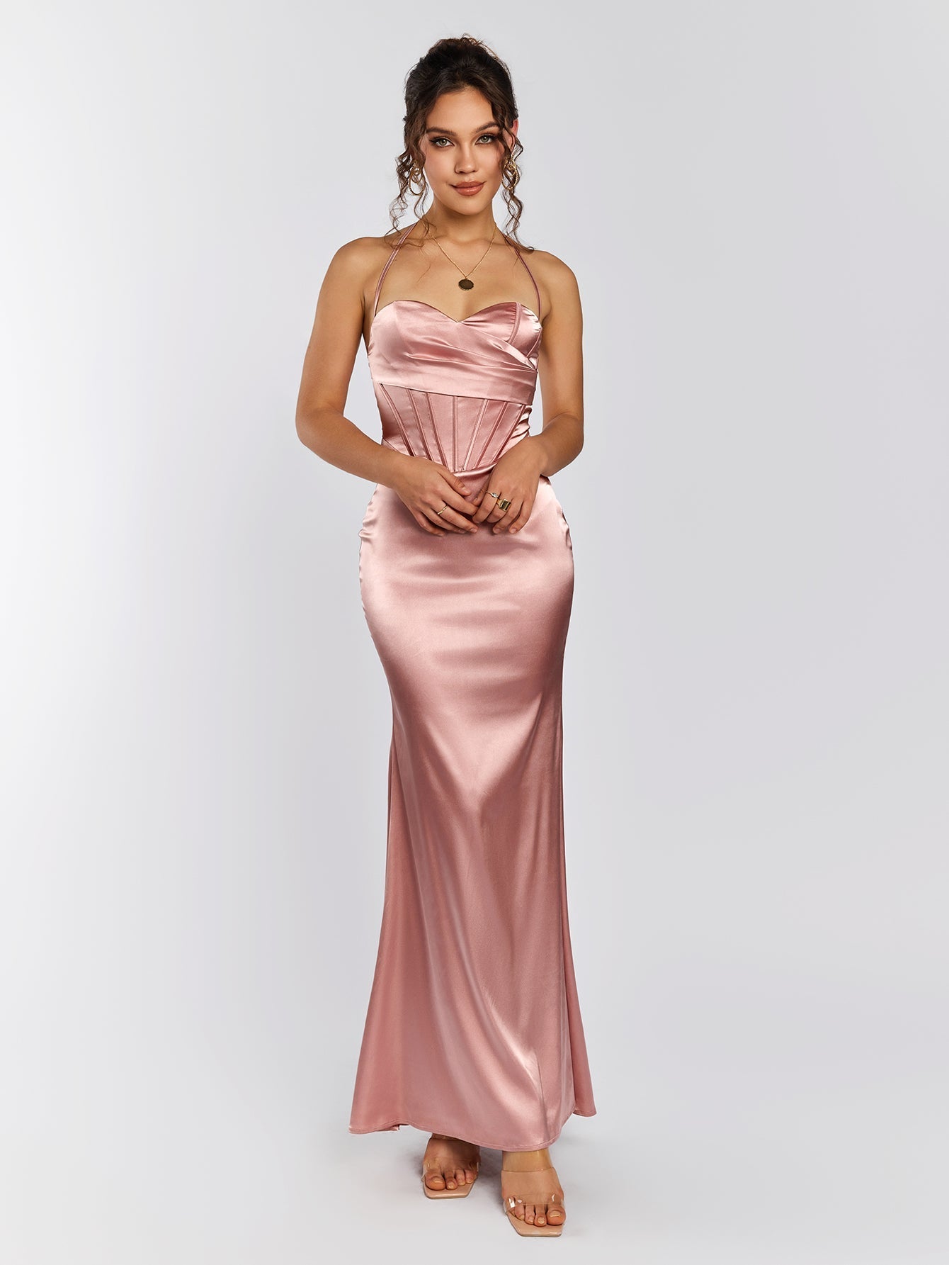 Woman wearing a pink satin floor-length mermaid gown with spaghetti straps and a corset bodice