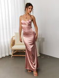 Woman posing in a pink satin floor-length mermaid gown with a corset bodice in an indoor setting