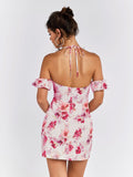 Back view of a woman in a white floral print mini dress with off-the-shoulder sleeves and a halter tie closure.