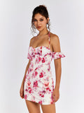 Full body shot of a woman posing in a white floral print mini dress with off-the-shoulder sleeves and halter neckline.