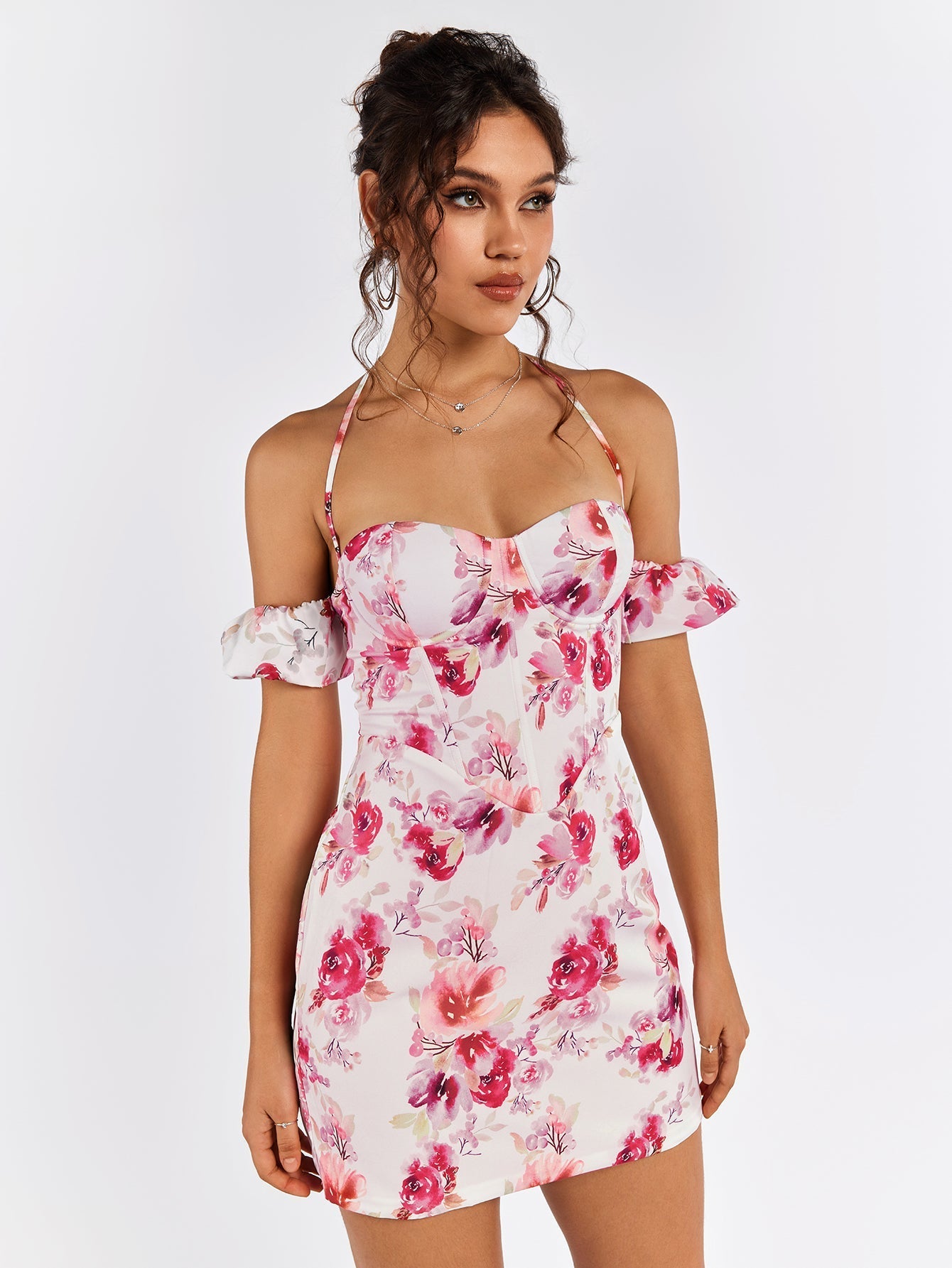 Close-up of a woman wearing a white floral print mini dress with off-the-shoulder sleeves and halter neckline.