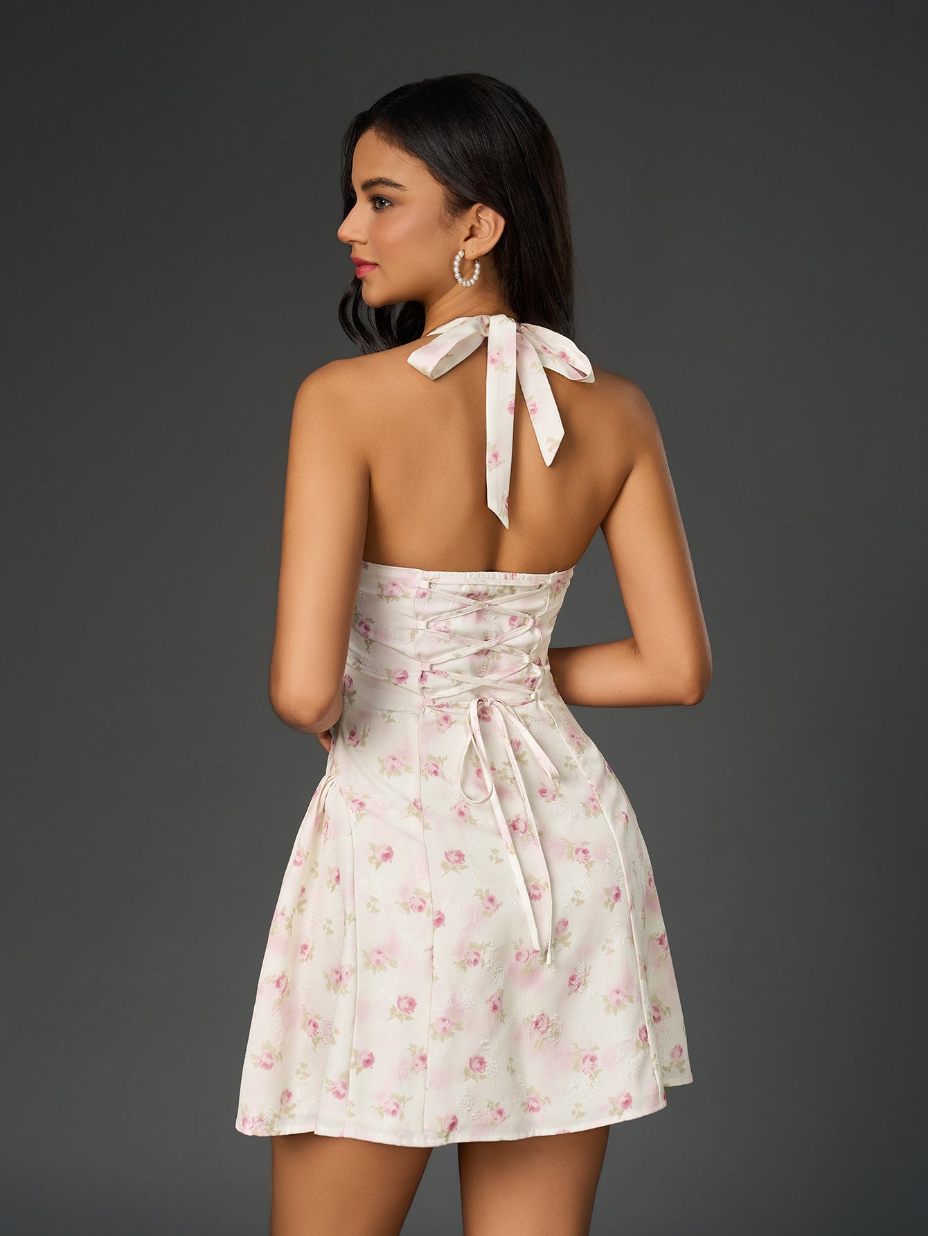 Back view of a woman in a white floral print halter dress with a corset tie closure