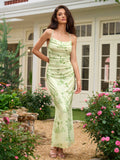 Woman wearing a light green floral print maxi dress with spaghetti straps and a cowl neckline, standing outdoors.