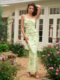 Woman posing in a light green floral print maxi dress with spaghetti straps and a cowl neckline.