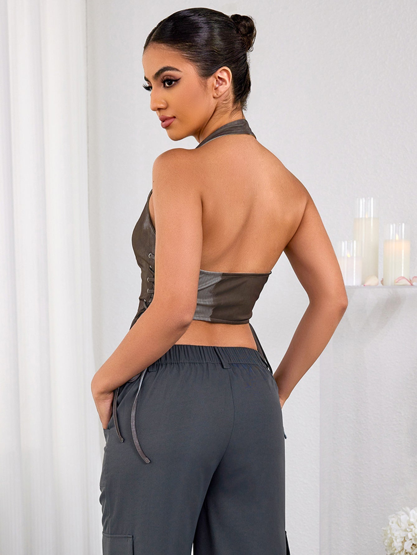 Back view of a woman wearing a brown halter neck cropped vest.