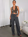 Full body shot of a woman wearing a brown halter neck cropped vest with zipper front and lace-up sides, paired with grey cargo pants.